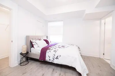 a white bedroom with a bed and a window at Luxury & Comfy Apartment, Mins Drive To All Niagara Falls Attraction in Niagara Falls