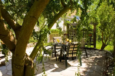 a table and chairs under a tree in a yard at Sapience Retreat & Apothecary in Niagara on the Lake