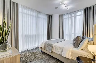 a bedroom with a bed and large windows at Prime Location - Stunning 2-bdrm Condo in Toronto