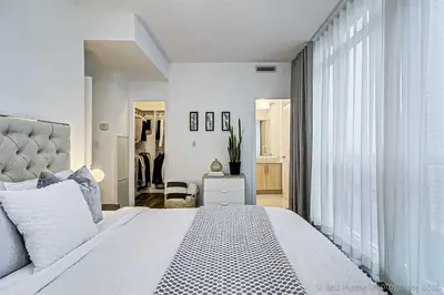 a white bedroom with a large bed and a window at Prime Location - Stunning 2-bdrm Condo in Toronto