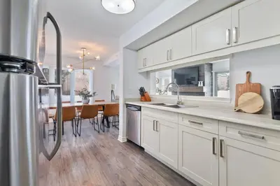 a kitchen with white cabinets and a dining table at Mountain Walk Chalet Across From Blue Mtn Village in Blue Mountains