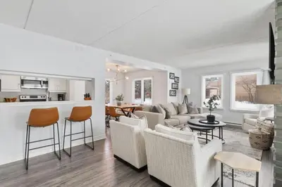 a living room with white furniture and a kitchen at Mountain Walk Chalet Across From Blue Mtn Village in Blue Mountains