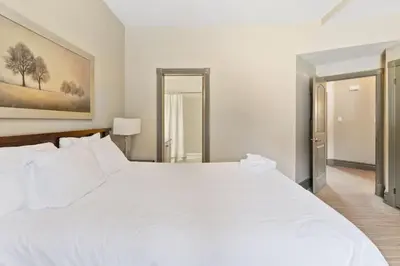 a bedroom with a white bed and a mirror at Blue Mtn Getaway in Historic Snowbridge Chalet in Collingwood