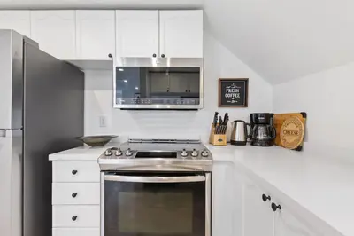 a white kitchen with a stove and a microwave at Luxury Blue Mtn Getaway w Indoor Sauna in Blue Mountains