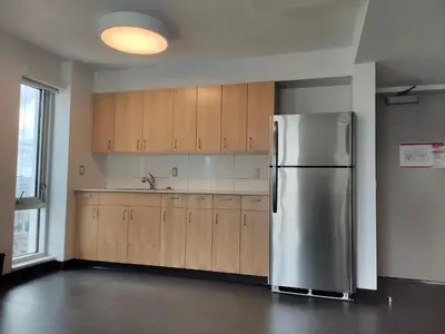 a kitchen with a stainless steel refrigerator and wooden cabinets at Toronto Metropolitan University-Daphne Cockwell Complex Residence in Toronto