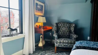 a bedroom with a chair and a desk and a window at Stone's Throw Stratford in Stratford