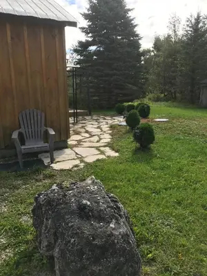 a stone walkway with a bench and a rock at Dreamers Writing Farm, 3 Wooded Acres, Hepworth in Sauble Beach