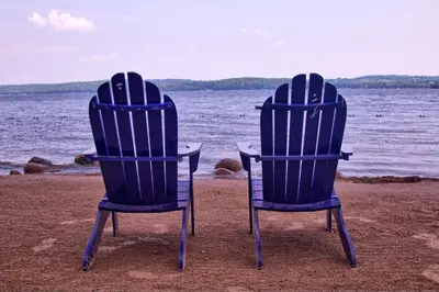 two chairs sitting on the beach near the water at Bellmere Winds Resort in Keene