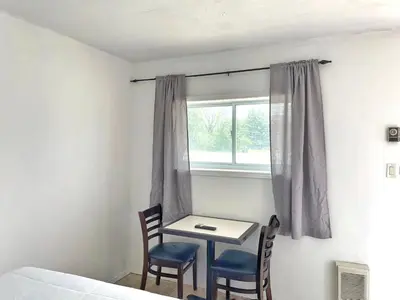 a bedroom with a table and two chairs and a window at Sunny Motel Port Elgin in Port Elgin
