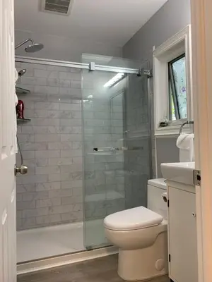 a bathroom with a toilet and a glass shower at Ambiance by the Falls Cozy Suite in Niagara Falls