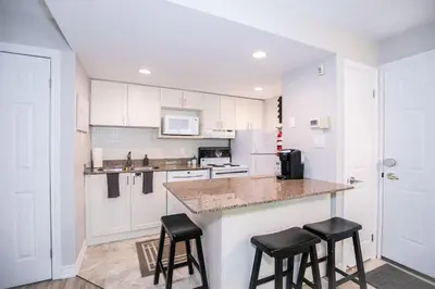 a kitchen with white cabinets and black stools at Slopeside Sanctuary - Ski In/Ski Out in Blue Mountains