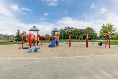 a playground with a slide and swings at Cozy 3 bedroom home perfect for small gatherings in Barrie