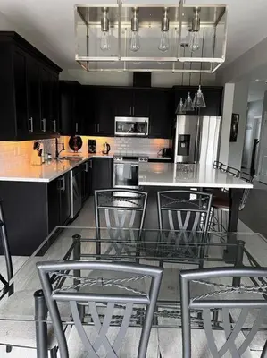 a kitchen with black cabinets and a table and chairs at Cozy 3 bedroom home perfect for small gatherings in Barrie
