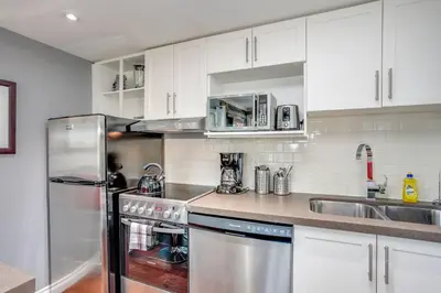 a kitchen with white cabinets and a stainless steel refrigerator at Blue Mountain Luxury Studio in Blue Mountains