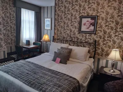 a hotel room with a bed and a chair at The King George Inn in Cobourg