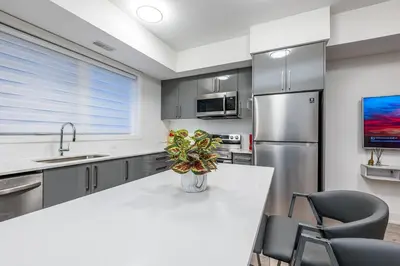 a kitchen with a white counter and a refrigerator at Exquisite 2 Bedroom Apt, mins to the falls. in Niagara Falls