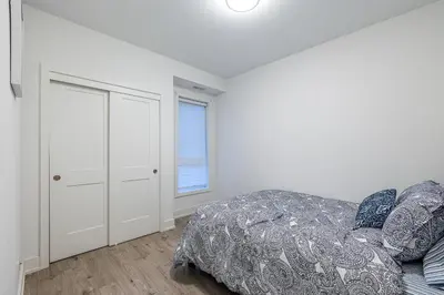 a white bedroom with a bed and a window at Exquisite 2 Bedroom Apt, mins to the falls. in Niagara Falls