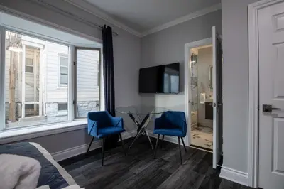 a bedroom with two blue chairs and a table and a tv at Niagara Luxury Suites in Niagara Falls