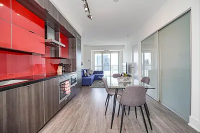 a kitchen with red cabinets and a table with chairs at RHD Luxury Condos-Downtown, CN Tower, Metro Toronto Convention Centre, Rogers Centre, Free Parking in Toronto