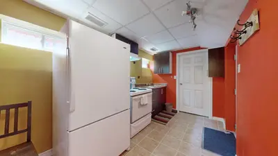 a kitchen with orange walls and a white refrigerator at ZARA's UNIQUE APARTMENT in Mississauga