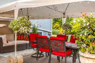 a patio with red chairs and a table under an umbrella at Nature Oasis Bar Room in Dundas