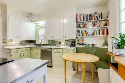 a kitchen with white cabinets and a wooden table at Four Bedroom Rosedale Home in Toronto