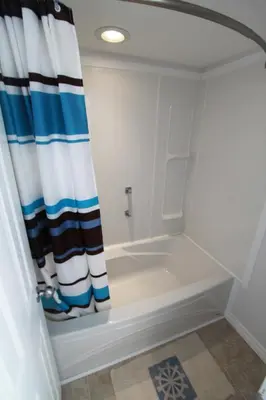 a bath tub with a shower curtain in a bathroom at Plovers Cove Cottage in Wasaga Beach