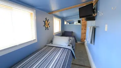 a small room with a bed and a tv at Plovers Cove Cottage in Wasaga Beach