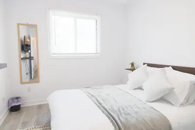 a white bed with white pillows and a window at Family-Friendly Boho Stay - Sleeps 10 - Near the Falls in Thorold