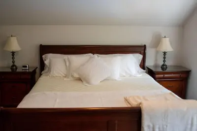 a bed with white pillows and two night stands at Upper Canada Coach House in Niagara on the Lake