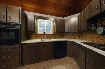 a kitchen with wooden cabinets and a sink and a window at Spacious 3 Plus 1 Bedroom 2 Bath Cottage Retreat with Fire Pit and Pool Table in Brighton