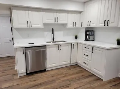 a kitchen with white cabinets and a stainless steel dishwasher at Guest Suite in Whitby in Whitby