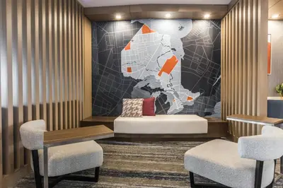 a hotel lobby with a bed and two chairs at Holiday Inn Express & Suites Toronto Airport South by IHG in Toronto