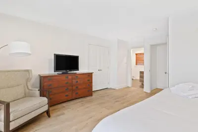 a bedroom with a television on a dresser with a chair at Rivergrass Home with Mountain and Golf Course Views in Blue Mountains