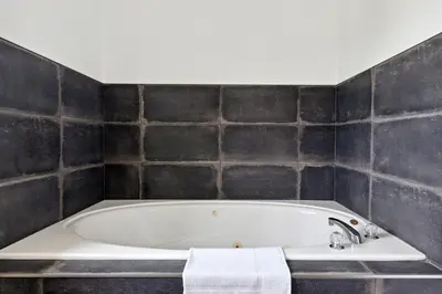 a bath tub in a bathroom with black tiles at 10 Bedroom Executive Chalet w Hot Tub in Blue Mountains