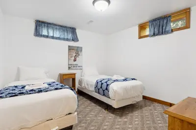 two beds in a room with white walls and windows at 10 Bedroom Executive Chalet w Hot Tub in Blue Mountains