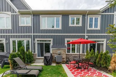 a house with a patio with a table and an umbrella at Exceptional 3 BDRM Townhome - 4 Seasons Rental in Collingwood