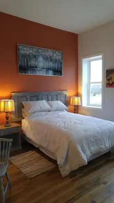 a bedroom with a large bed with orange walls at Canalside Restaurant & Inn in Port Colborne