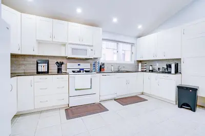 a white kitchen with white cabinets and appliances at Furnished Family Home near Toronto - Great Location Game Room - Backyard - Parking & Self Checkin in Pickering
