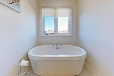 a white bath tub in a bathroom with a window at NEWLY BUILT LUXURIOUS 3BRM TOWN HS/AIRPORT/PARKING in Brampton
