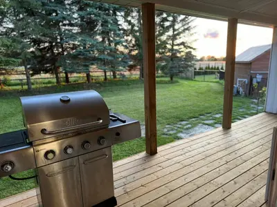 a grill on a deck with a view of a yard at Farmhouse Resort in Midhurst