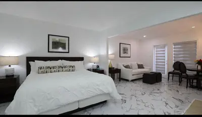 a white bedroom with a bed and a living room at Carriage Hills Retreat Rental in Edgar