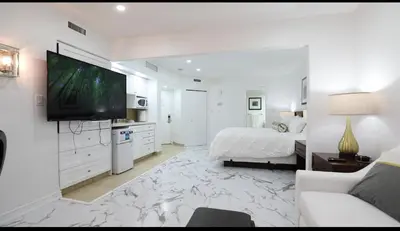 a white bedroom with a bed and a flat screen tv at Carriage Hills Retreat Rental in Edgar