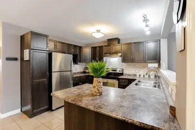 a kitchen with wooden cabinets and a kitchen island with a plant at Nimo Homestay in Guelph