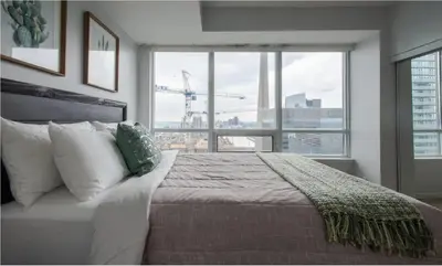 a bedroom with a large bed and a large window at Toronto Downtown Core Two Bedroom Condo with CN Tower View, Free Parking in Toronto