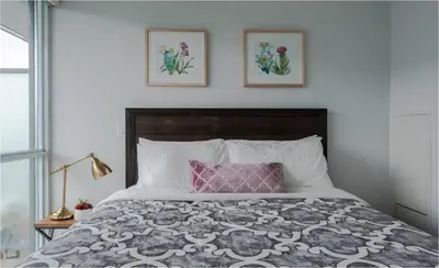 a bed with a pink pillow and two pictures on the wall at Toronto Downtown Core Two Bedroom Condo with CN Tower View, Free Parking in Toronto