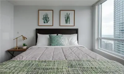 a bedroom with a large bed and two windows at Toronto Downtown Core Two Bedroom Condo with CN Tower View, Free Parking in Toronto