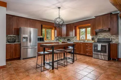 a kitchen with wooden cabinets and stainless steel appliances at Unique Log House by the Lake, Retreat with Spa Amenities near Presque'ile Provincial Park in Brighton