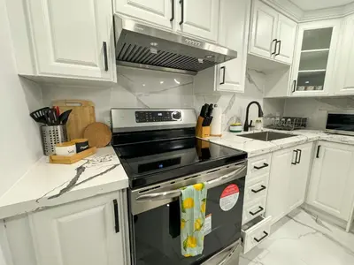 a kitchen with white cabinets and a stove top oven at The Khan Villa in Whitby