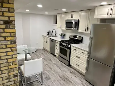 a kitchen with a stainless steel refrigerator and a table at Adorable 1 Bedroom Suite With Kitchen Fireplace in Cambridge